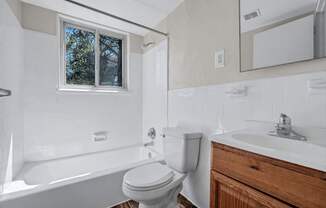 A white toilet sits next to a white sink in a bathroom at Highland Ridge Apartments, Maryland