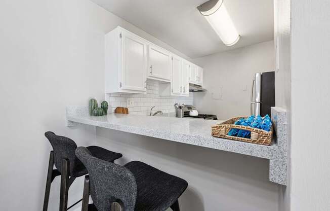 A kitchen with white cabinets and a counter with a basket of blue cloths on it.