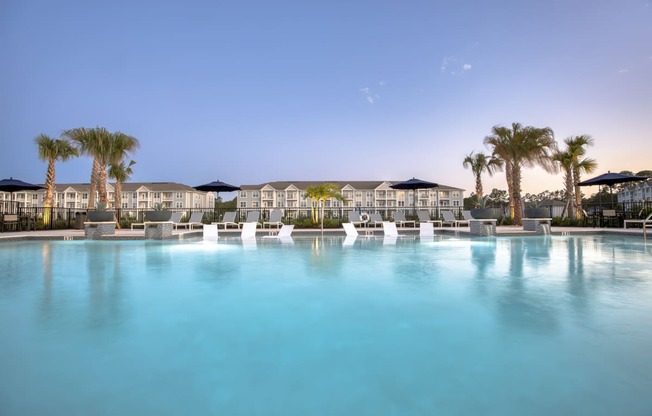 a large swimming pool with palm trees and buildings in the background