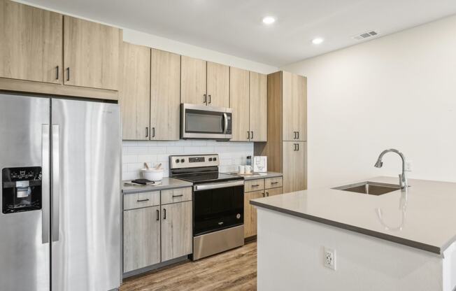 a kitchen with stainless steel appliances and wooden cabinets at Drift, Daytona Beach, FL, 32117