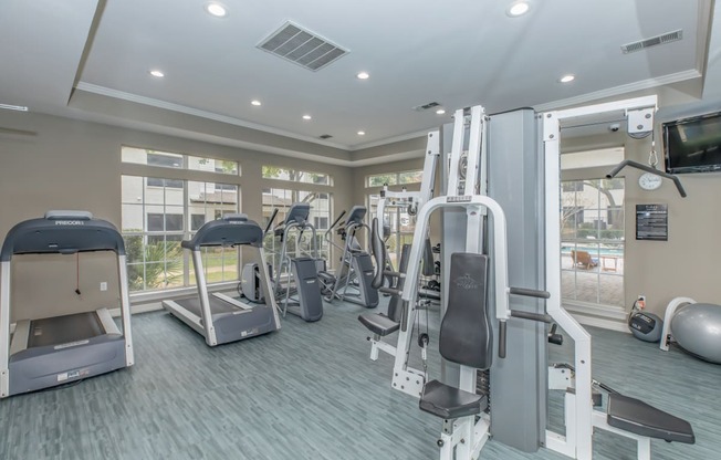 a gym with cardio equipment and a flat screen tv