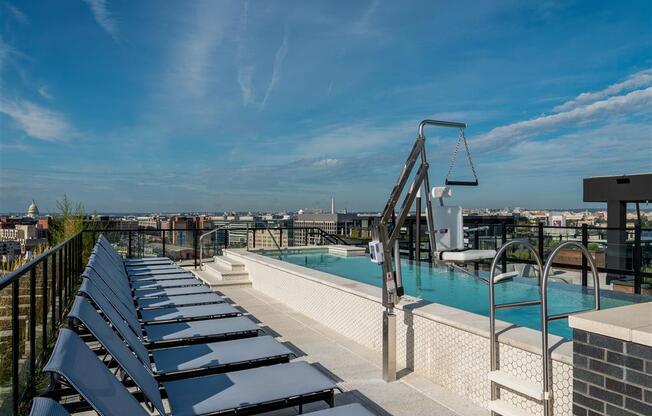 a rooftop pool with lounge chairs and a city in the background