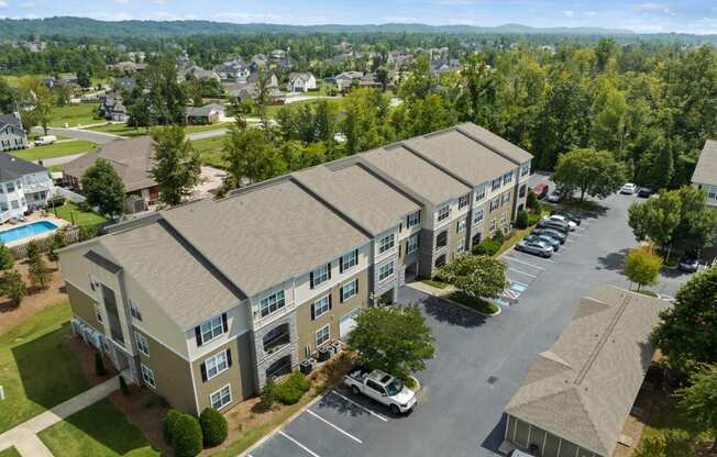 an aerial view of an apartment complex with a swimming pool and parking lot