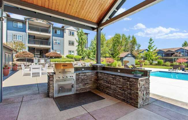 A patio with a stone wall and a grill is shown.