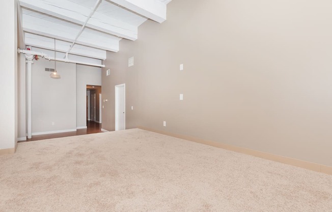 an empty living room with a beige carpet and white walls