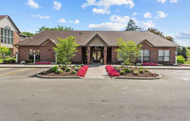 A building with a red brick facade and a large front yard with red flowers.