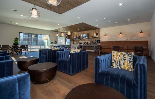 A modern living room with blue velvet chairs and a wooden ceiling.