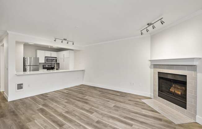 a living room with a fireplace and a kitchen in the background