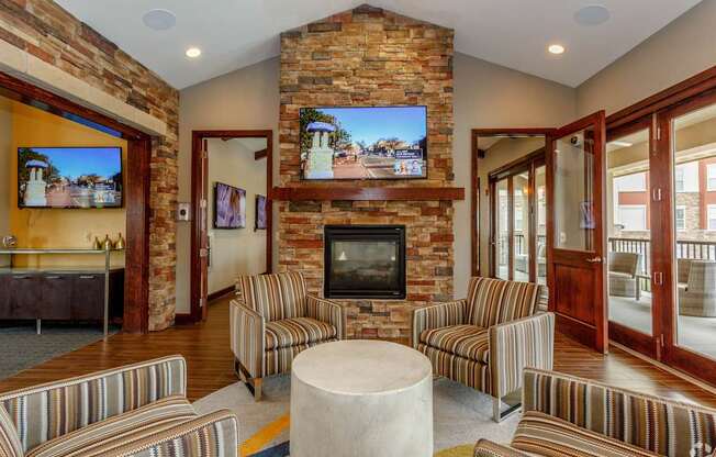 A living room with a stone fireplace and striped couches.