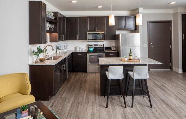 a kitchen with dark cabinets and a large island with a breakfast bar