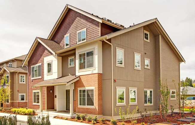 A modern two-story house with a red brick base and beige siding.