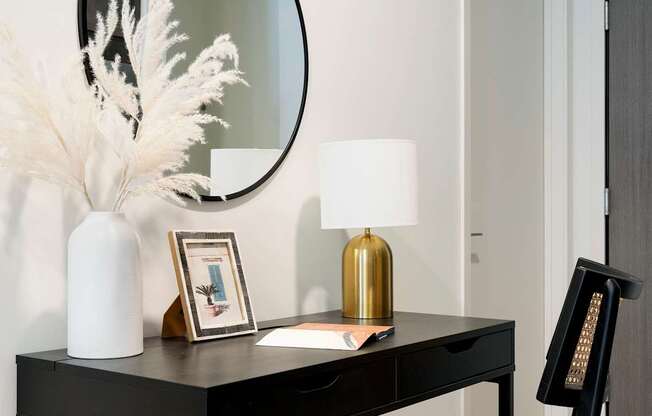 A black desk with a white chair and a round mirror above it.