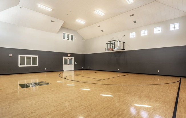a large gym with a basketball hoop and wood floors
