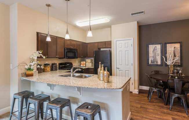 an open kitchen and dining area with stools and a granite counter top