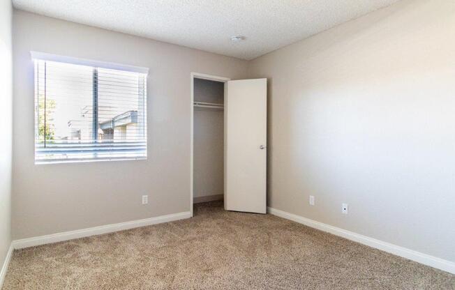 an empty room with a window and a closet