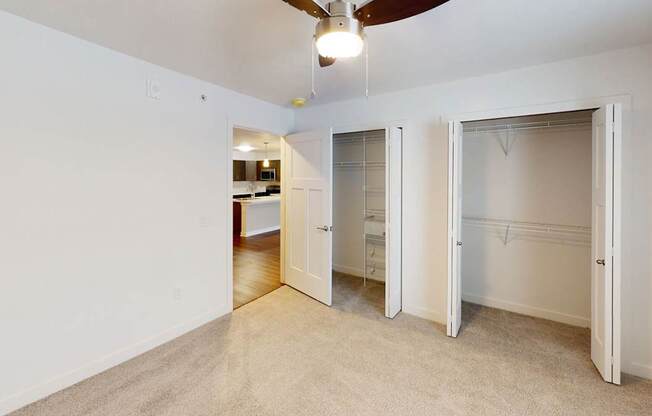 A bedroom with a ceiling fan and two large closets at Meadowbrooke Apartment Homes in Kentwood, MI 49512