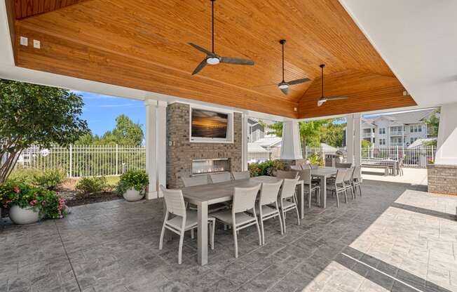 a covered patio with a table and chairs and a fireplace