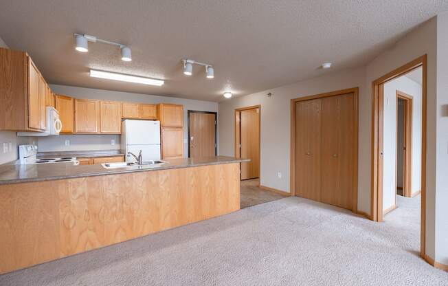 A kitchen with wooden cabinets and a countertop. Fargo, ND East Bridge Apartments
