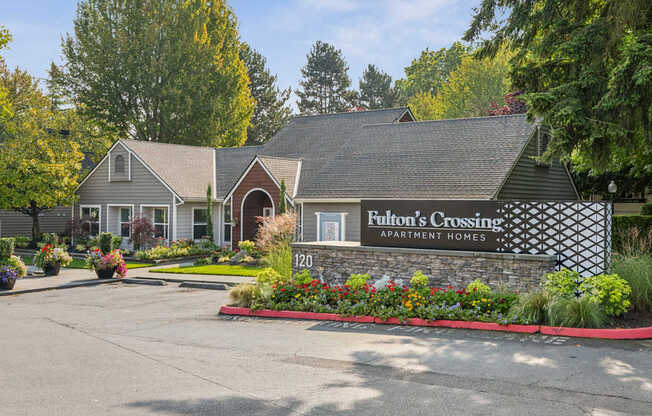 A sign for Fulton's Crossing Apartment Homes is in front of a house.