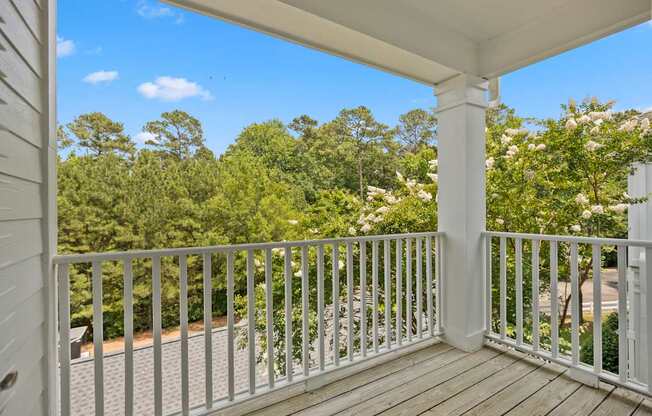A white porch with a white railing and a view of trees.