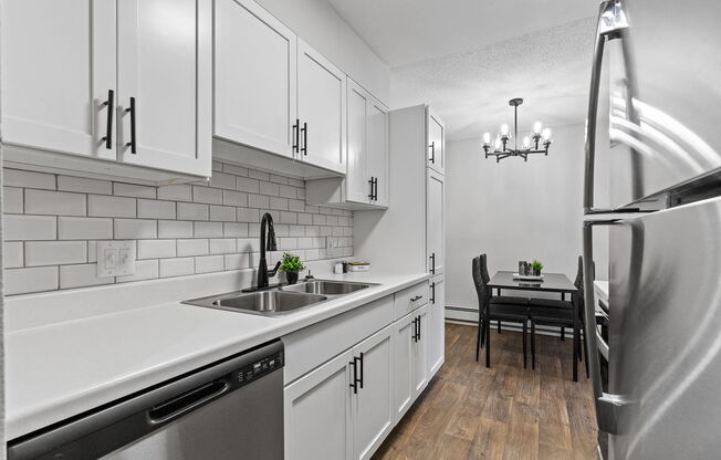 a kitchen with white cabinets and stainless steel appliances and a sink