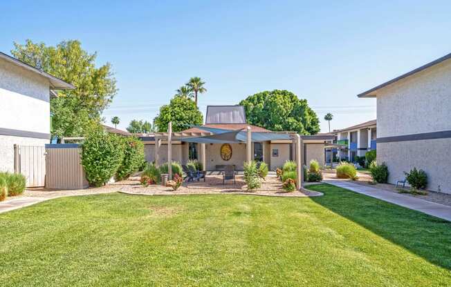 a yard with a table and chairs in front of a house