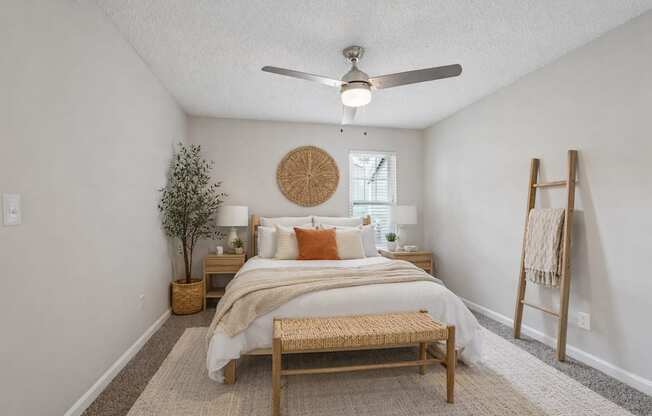 A bedroom with a bed, a bench, and a fan.