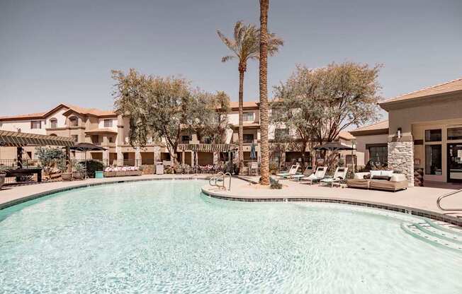 A pool surrounded by palm trees and lounge chairs.