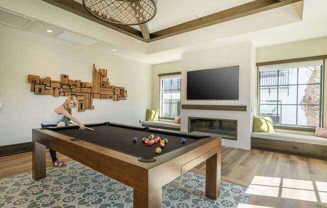 a woman playing a pool table in a living room with a tv