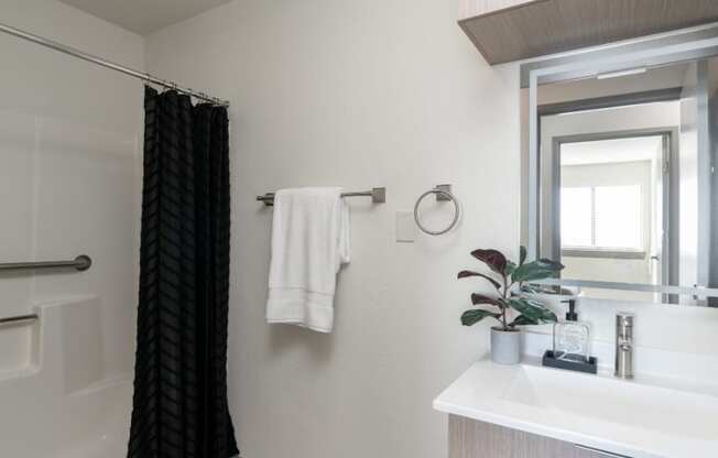 a bathroom with a white sink and a shower and a black shower curtain
