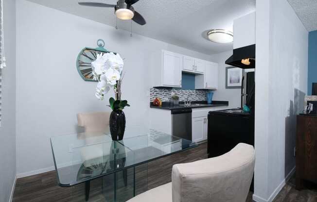 Fifteen 50 apartments Las Vegas open concept dining area and kitchen with white cabinets and modern glass dining table with white orchid