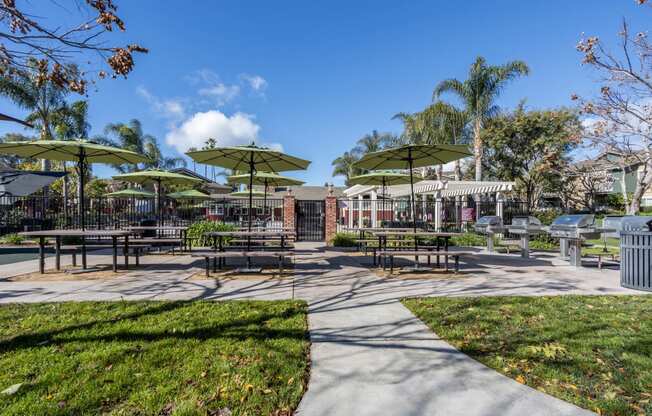 a picnic area with tables and umbrellas in a park