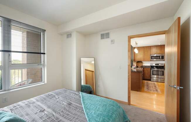 a bedroom with a large window and a door to a kitchen