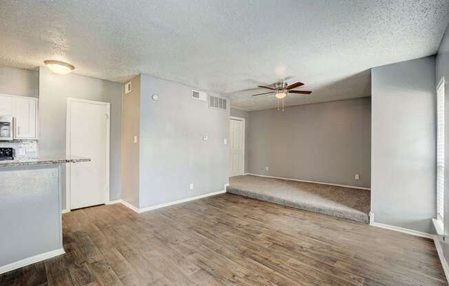 an empty living room and kitchen with a ceiling fan