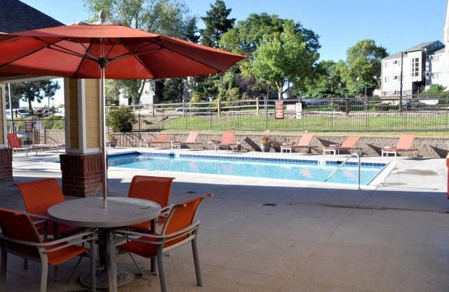 North Creek Apartments pool and round patio table with orange umbrella and chairs