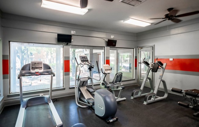 a gym with various exercise equipment and windows at The Summit Apartments, Memphis, TN, 38128