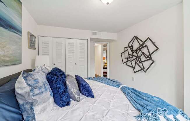 a bedroom with white walls and a bed with blue blankets and pillows