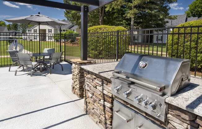 a patio with a grill and a table with chairs