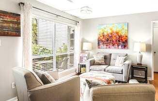A living room with a couch, chair, and a painting on the wall.