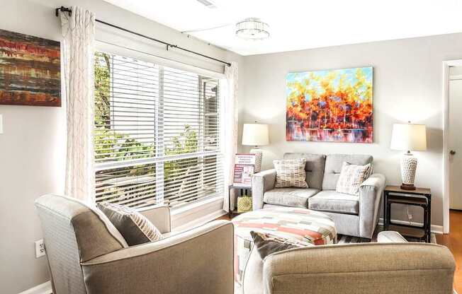 A living room with a couch, chair, and a painting on the wall.