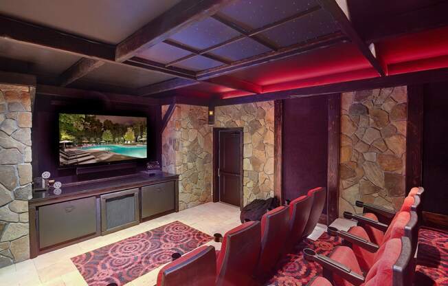 a media room with a large screen tv and a stone wall