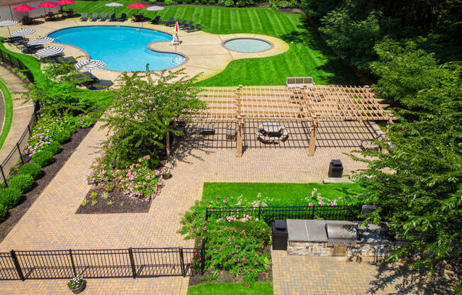 a garden with a swimming pool and a lawn with benches