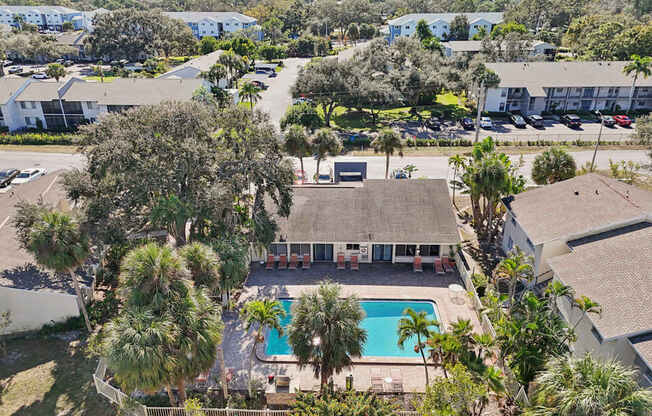 A swimming pool is surrounded by palm trees and a building.