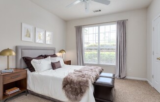 View of Bedroom, Showing Layered Bedding, Ceiling Fan, and Window View at Retreat at Peachtree City Apartments