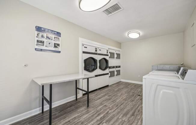 a washer and dryer in a laundry room with white walls and wood floors