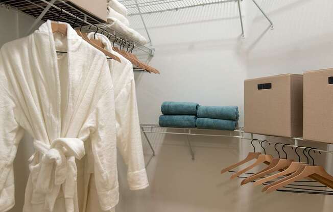 A white bathrobe hanging on a rack in a white room.