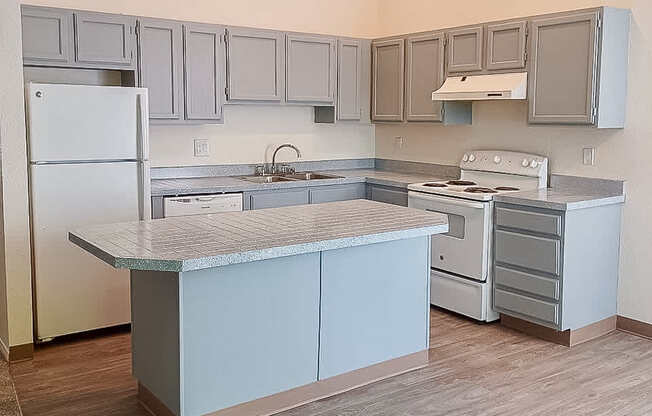 A kitchen with a white refrigerator and a marble island.