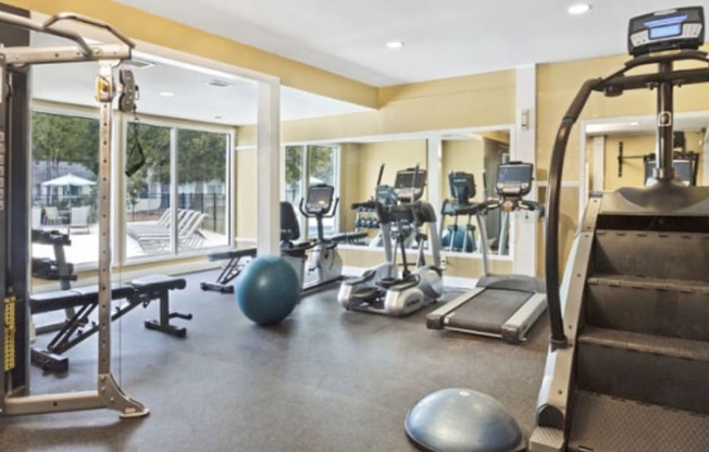 a gym with cardio equipment and weights in a building with windows