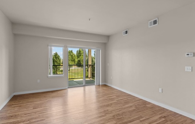 a bedroom with hardwood floors and a sliding glass door to a balcony