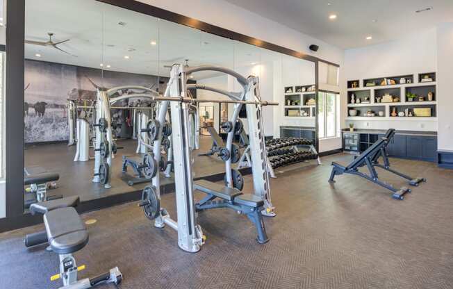 a gym with weights and other exercise equipment in a building with mirrored walls